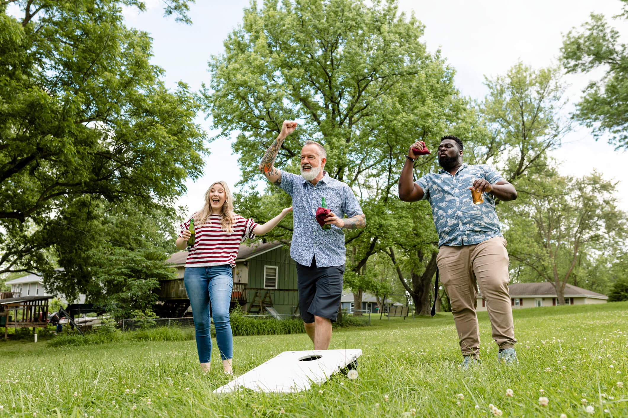people playing cornhole in the backyard at a party