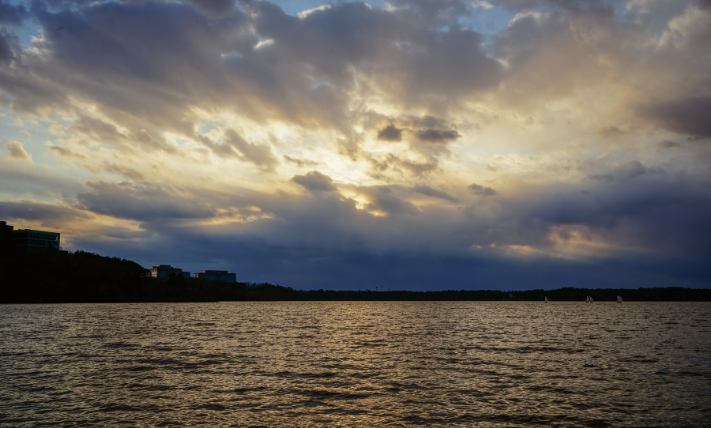 The sun peaking through storm cloud over a lake