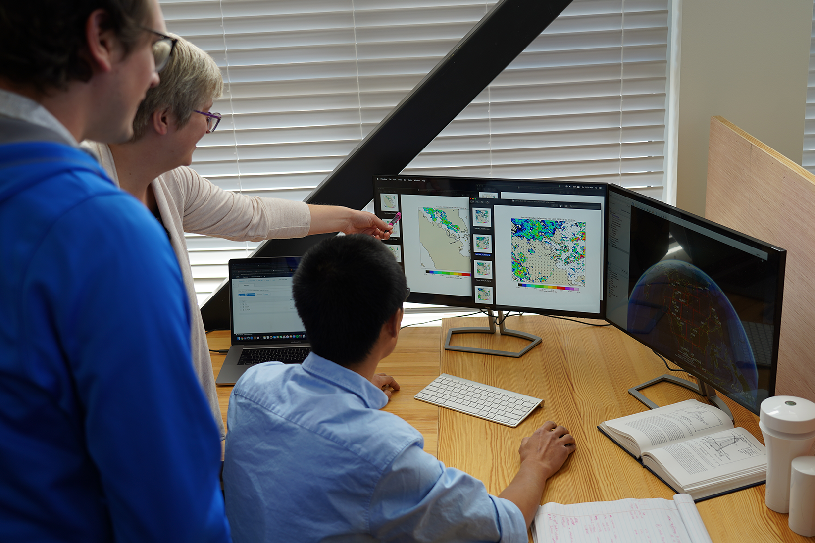 Three weather forecasters looking at weather data on their computers