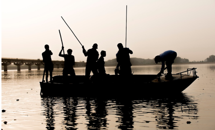Large group of men in a small fishing boat on a river